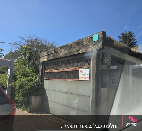 שער חשמלי עם שלט אזהרה ואזור חניה
